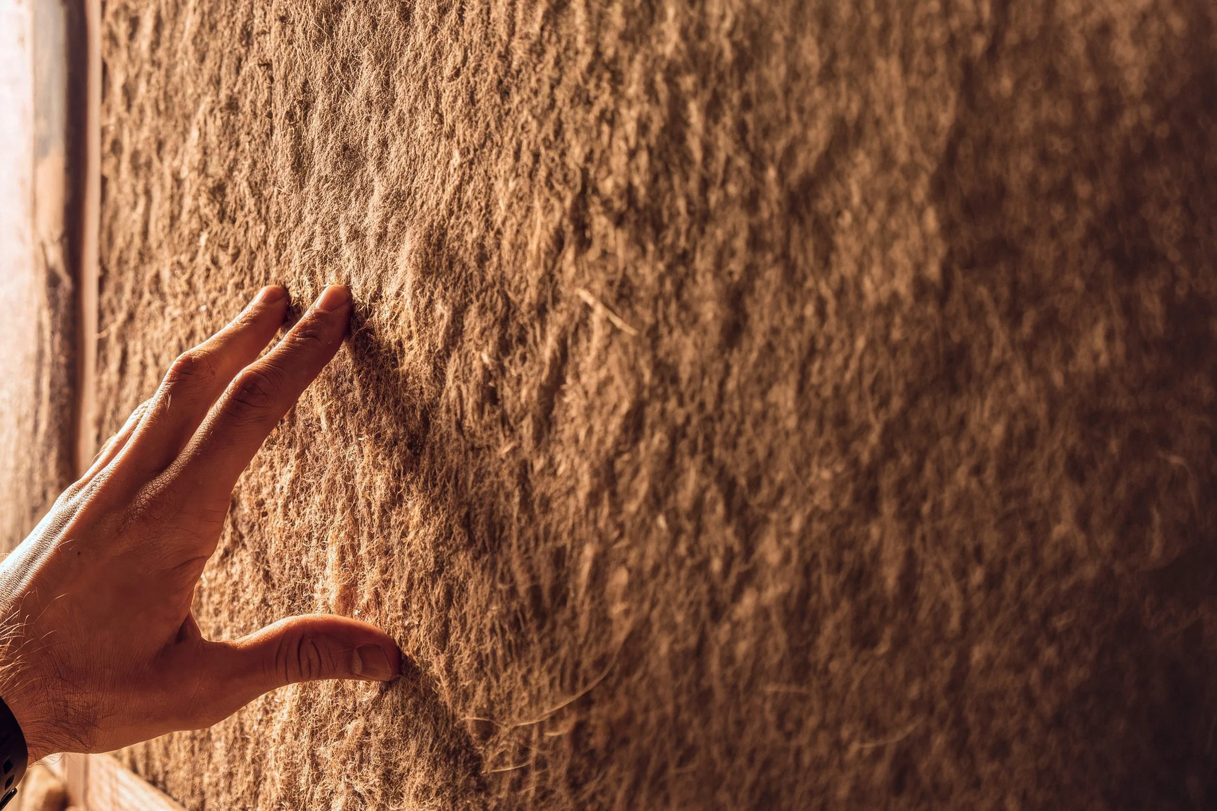 Una mano sobre un material natural — construir con la tierra